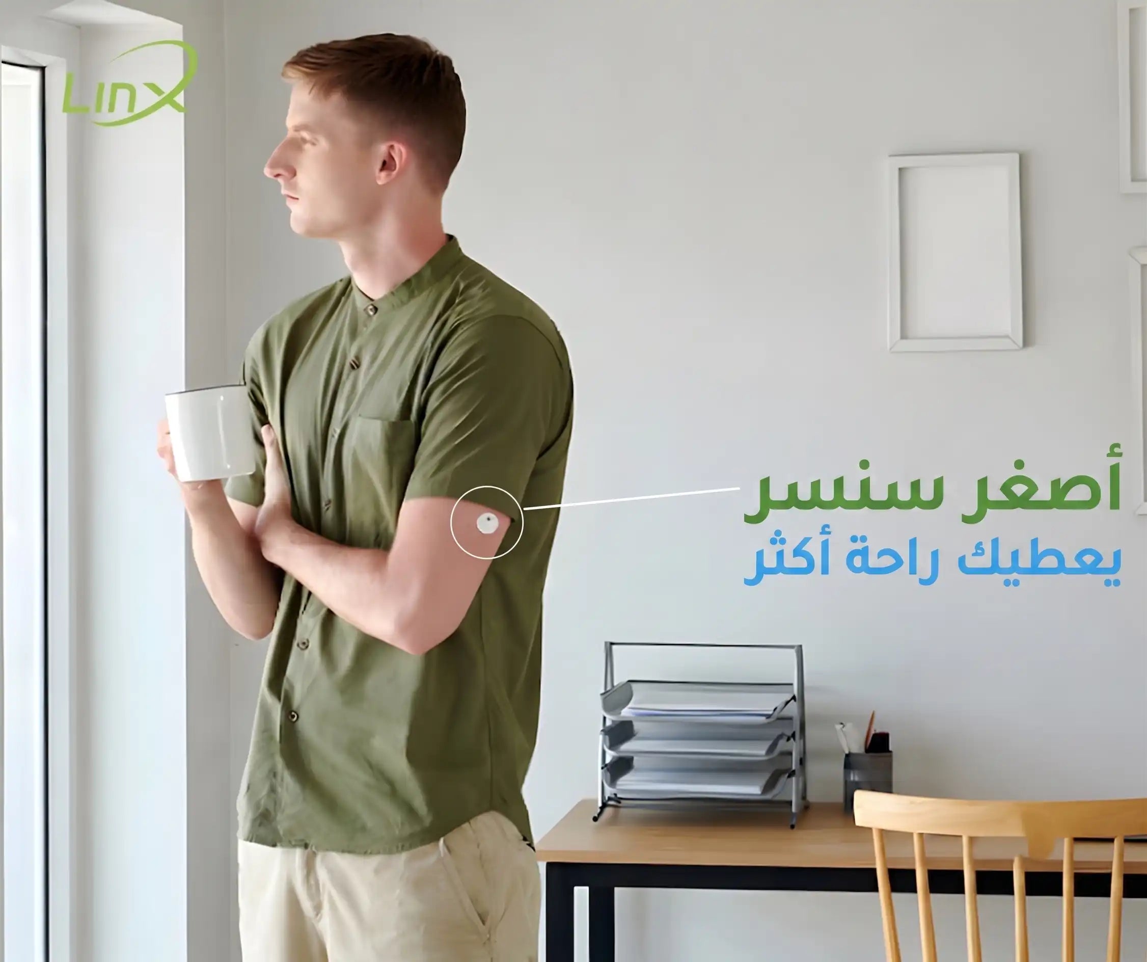 Man with arm sensor holds mug while looking out window.